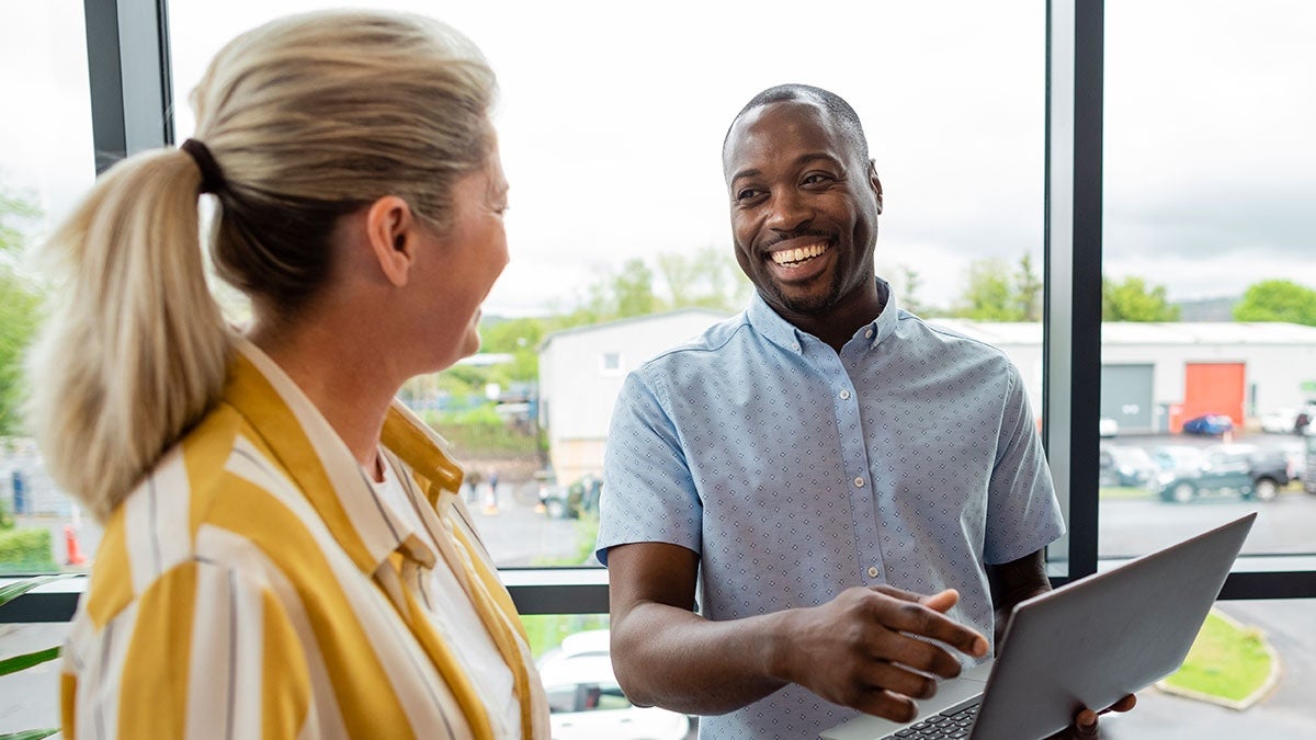 Smiling employee having a conversation with his colleague