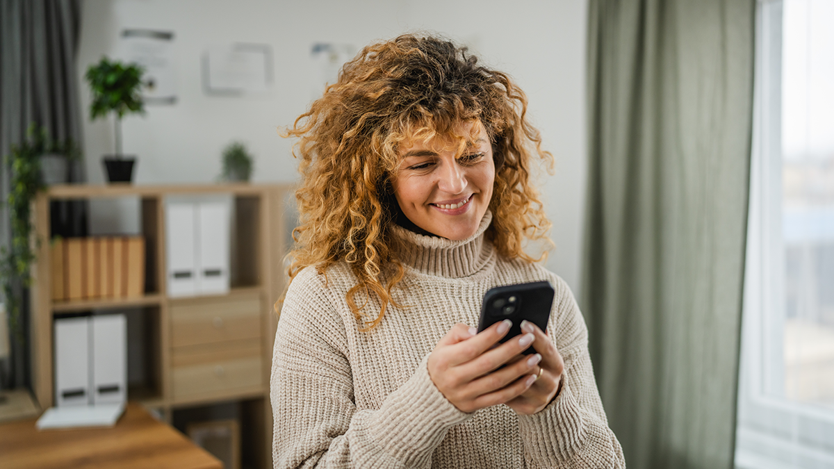 A woman smiling at her phone