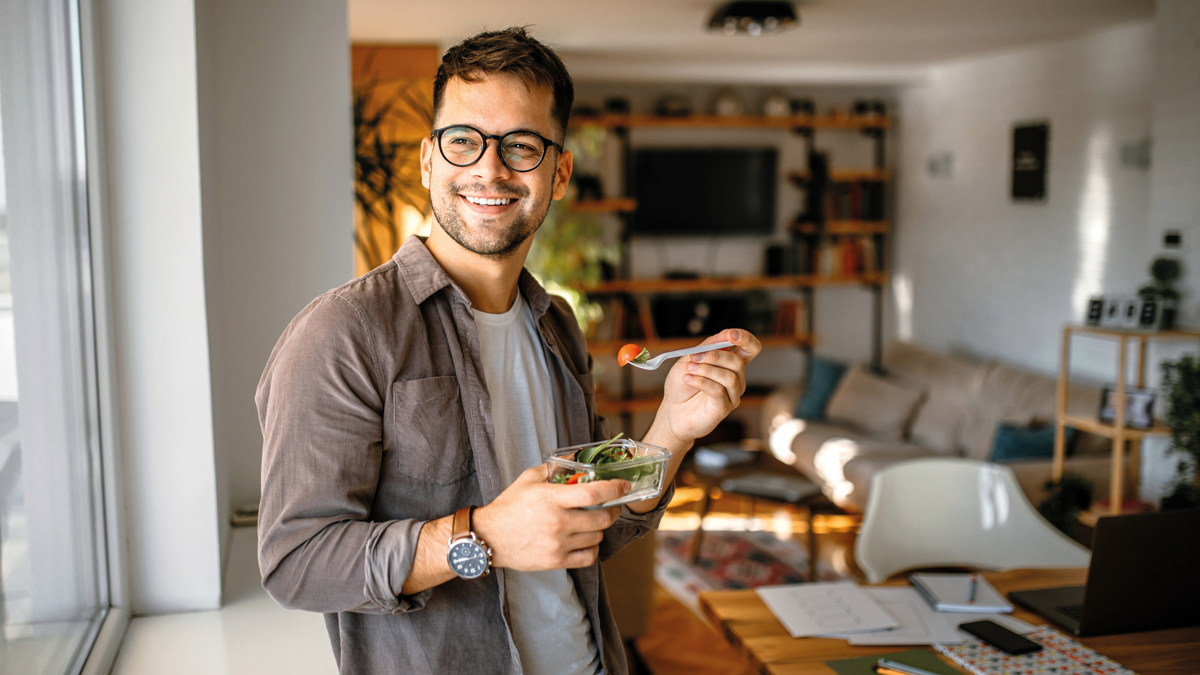 Man wearing glasses holding a pot of food
