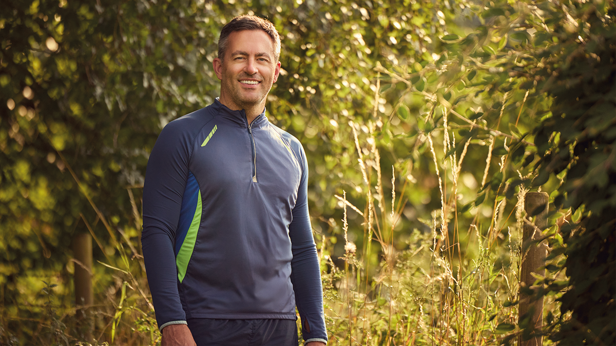Man smiling in sportswear in front of trees