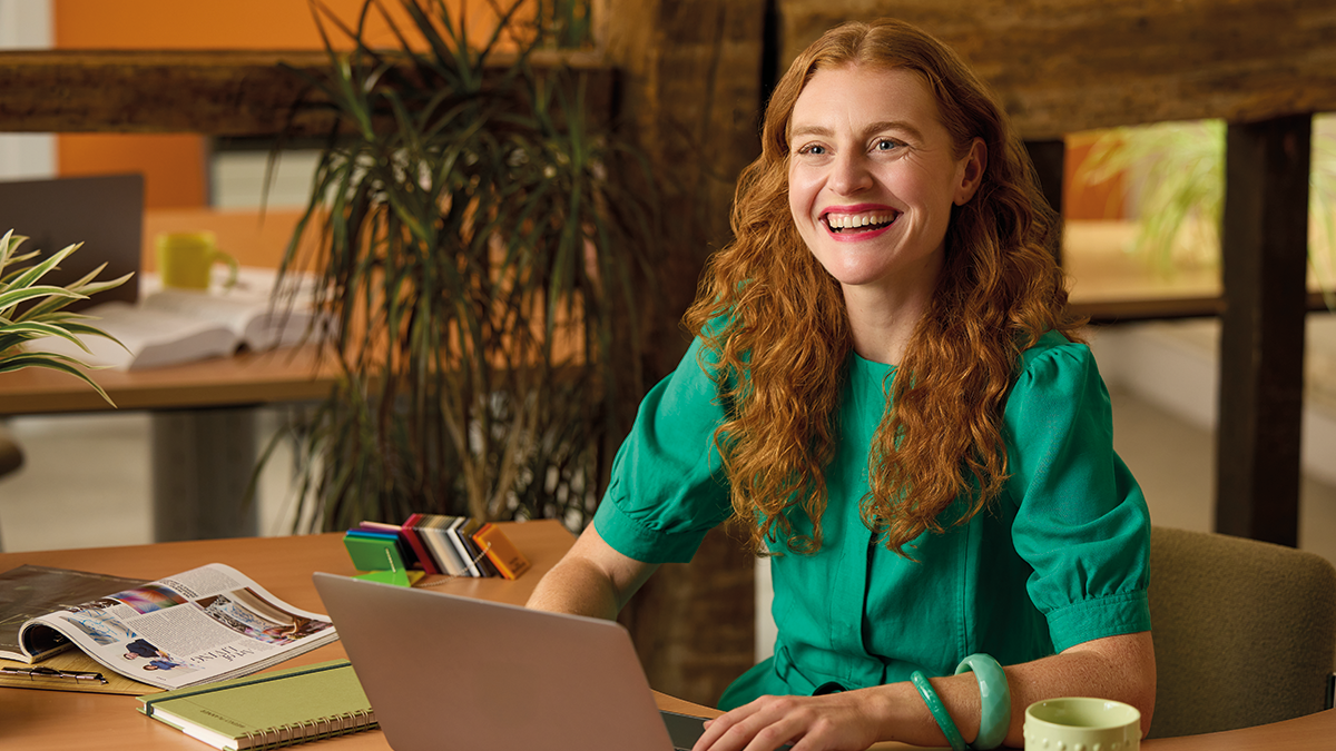Woman smiling sat in office with laptop