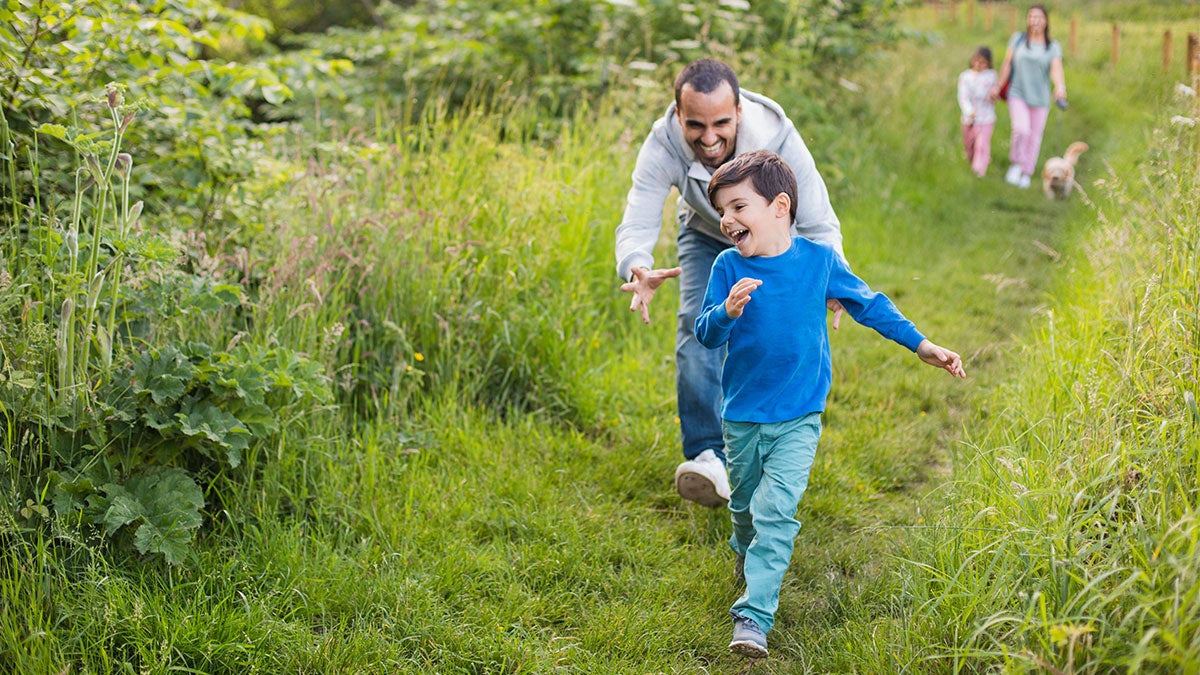 Father playing with son running on the grass