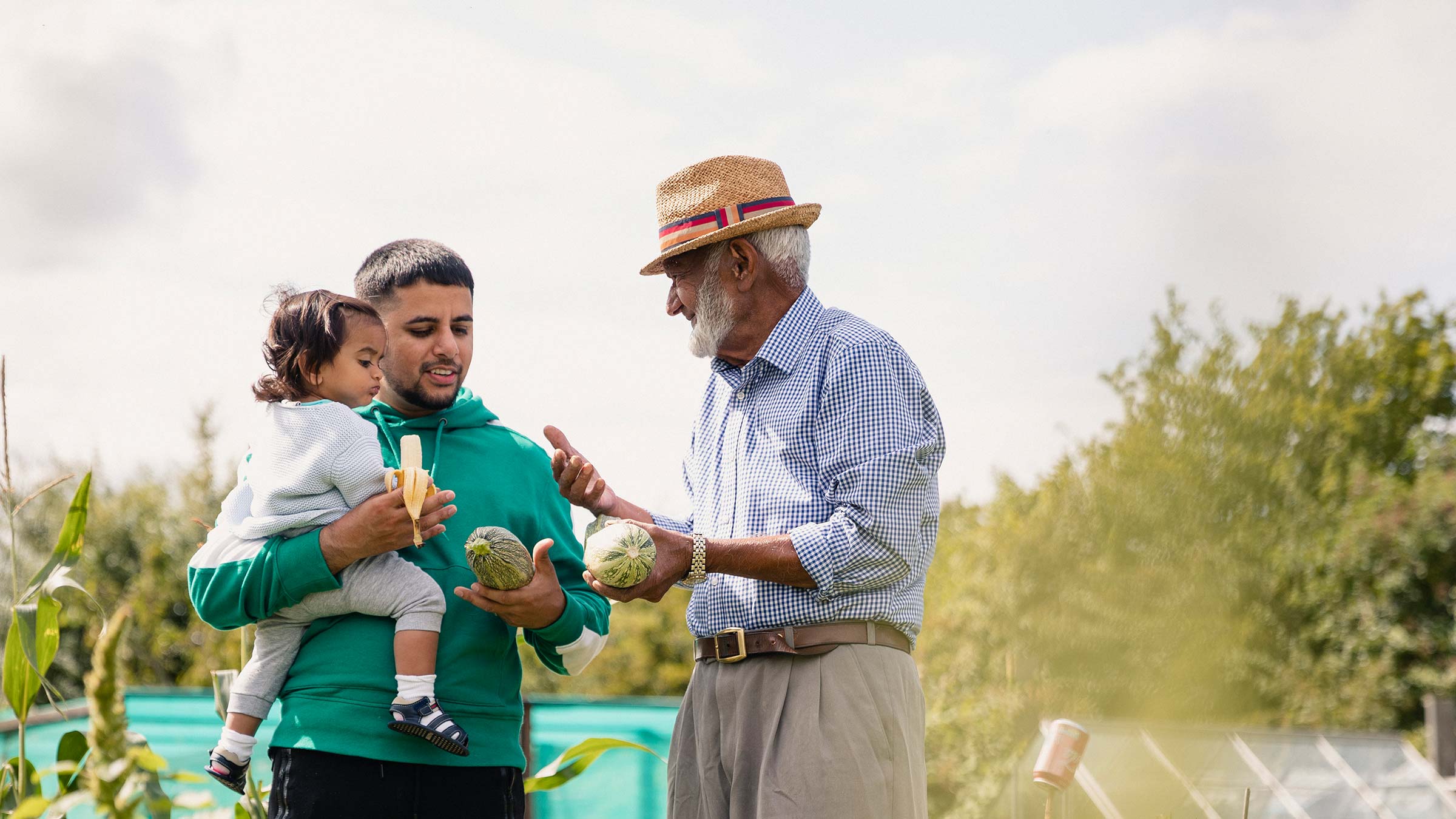 Father and daughter with Grandfather discussing vegetables in an allotment