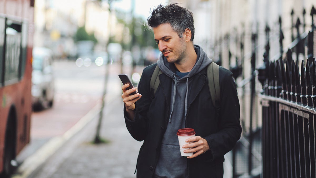 Man catching bus, on phone with coffee