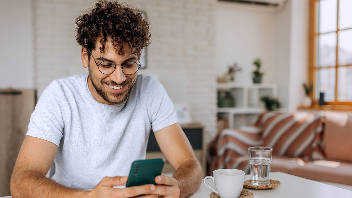 Man smiling typing on his mobile phone