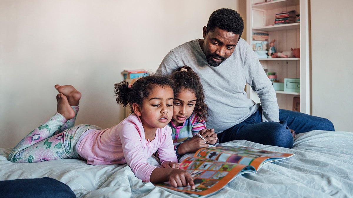 Father reading bed story to his daughters