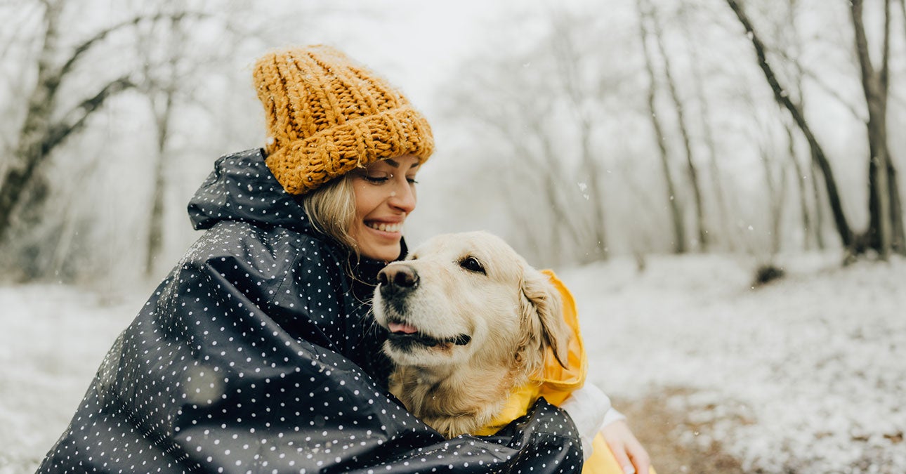 A woman holding a dog in the snow