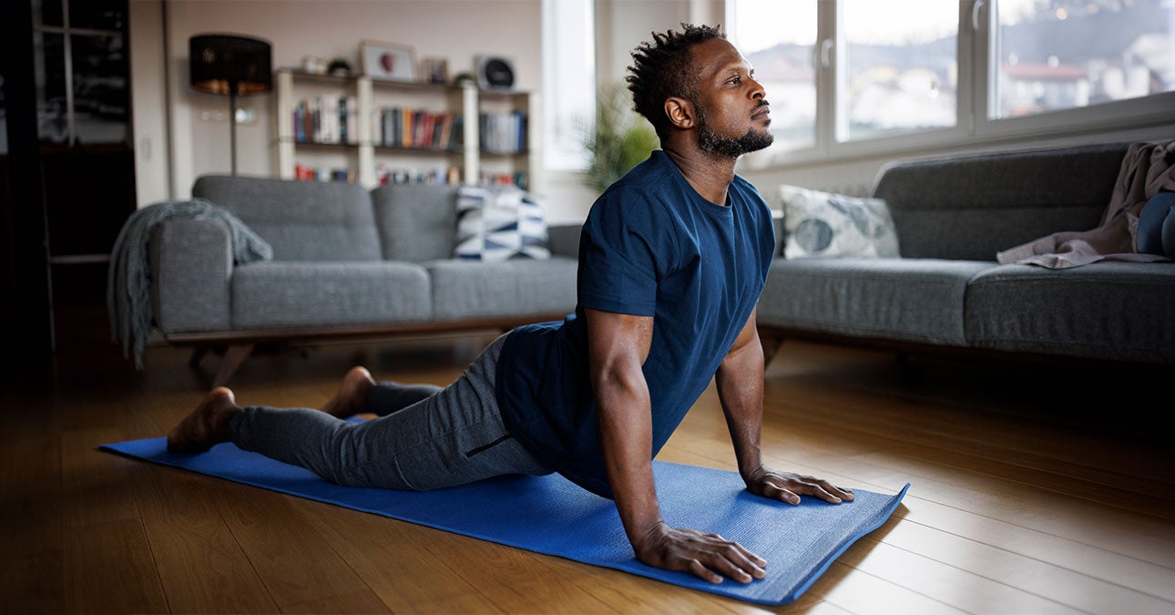 Man stretching on a yoga mat at home