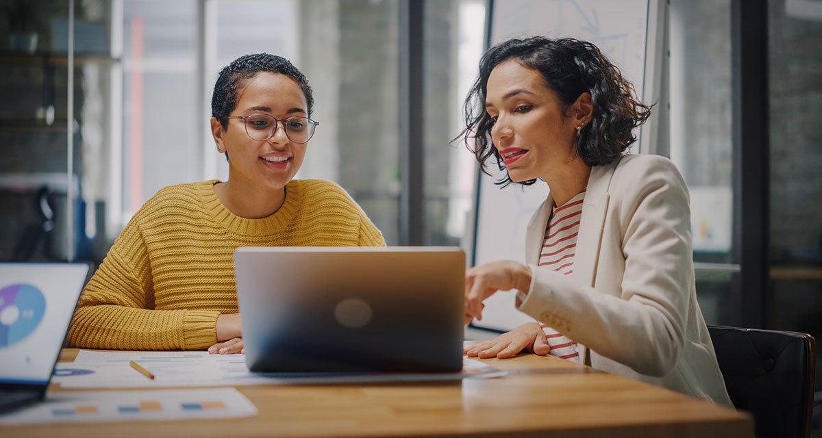 Two employees in a meeting pointing at the laptop