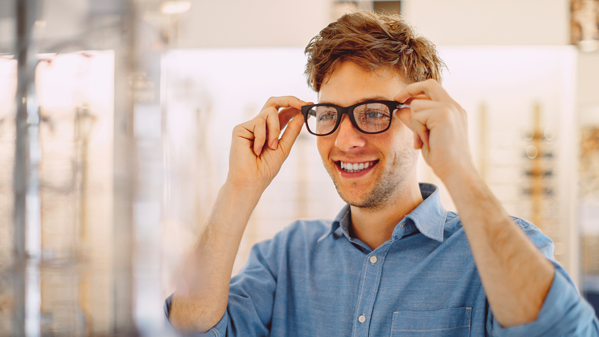 Man smiling while trying on glasses
