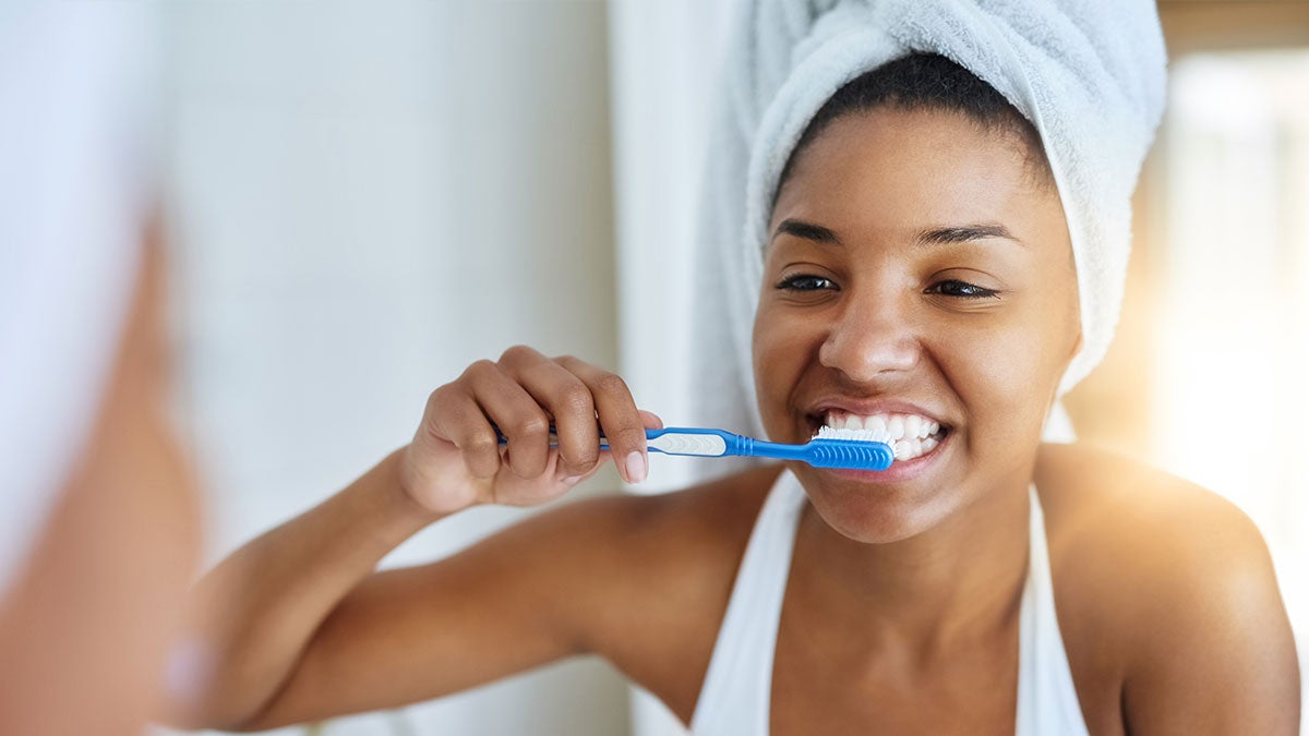 Woman brushing her teeth and smiling