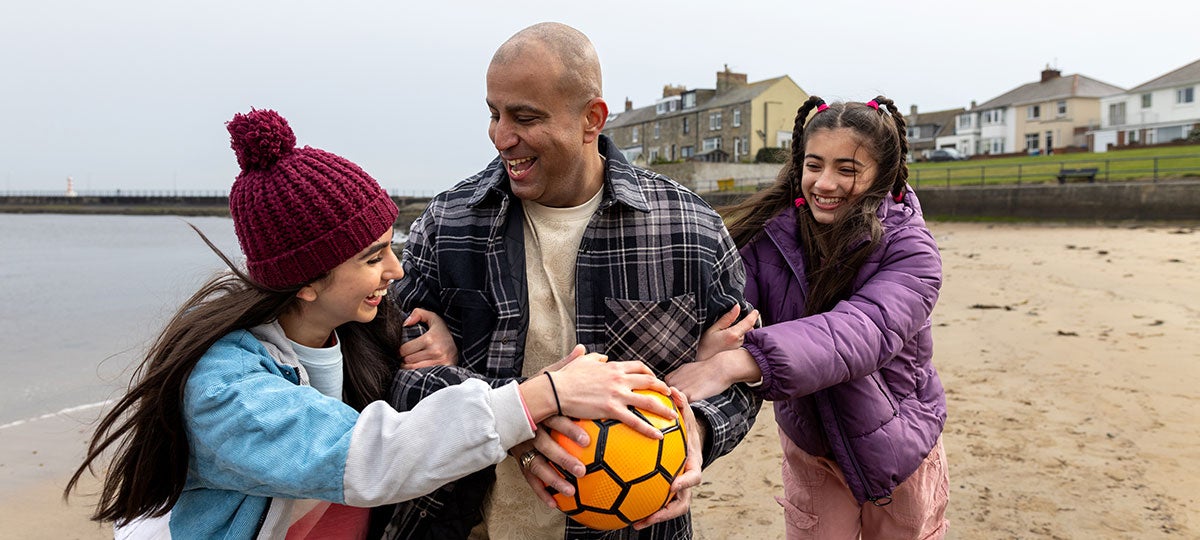A man holding a football ball with two girls