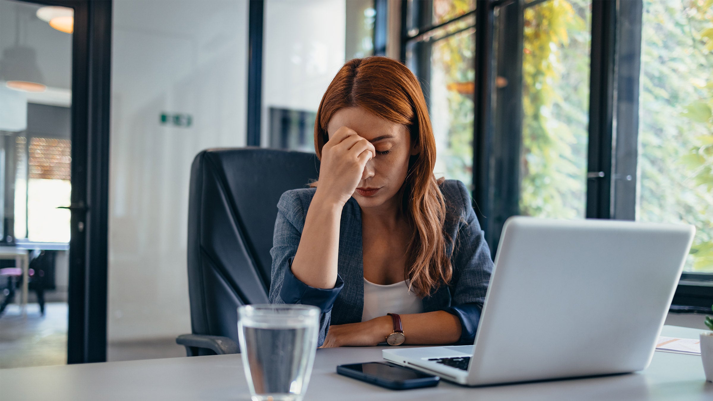 Office worker holding her head looking down