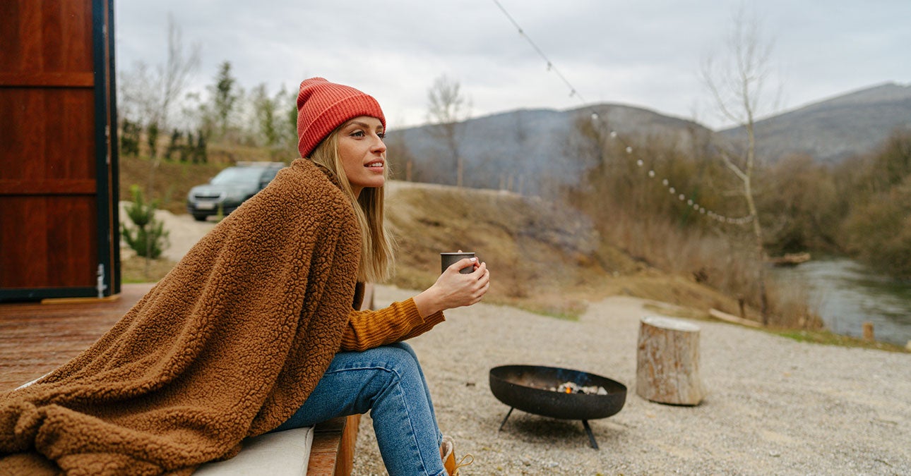 A woman sits on a bench and holds a cup