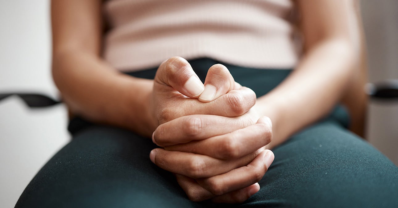 An image of a person sitting with their hands clasped in their lap.
