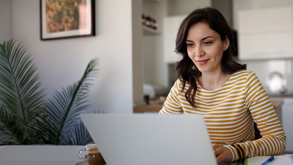 A woman in a yellow shirt looking at a laptop