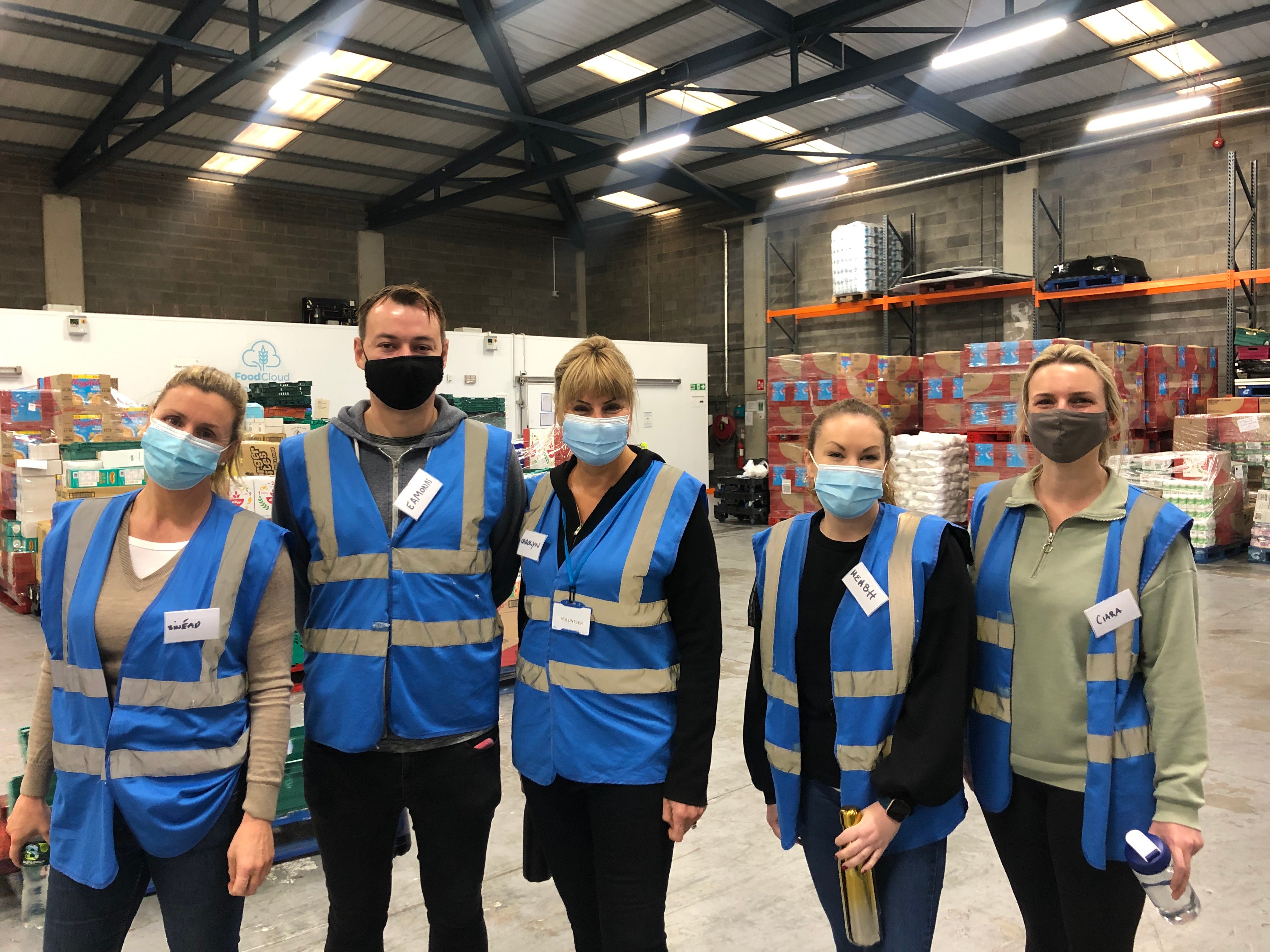 Team-of-volunteers-with-high-vis-vests-standing-in-the-warehouse
