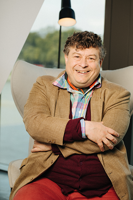 Rory Sutherland sitting in a chair smiling