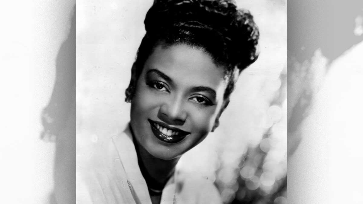 A black and white profile shot of Hazel Scott smiling.