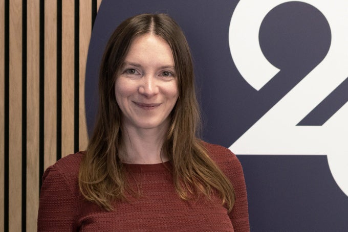 Headshot of Maria Thorpe, with the 26 logo in the background.