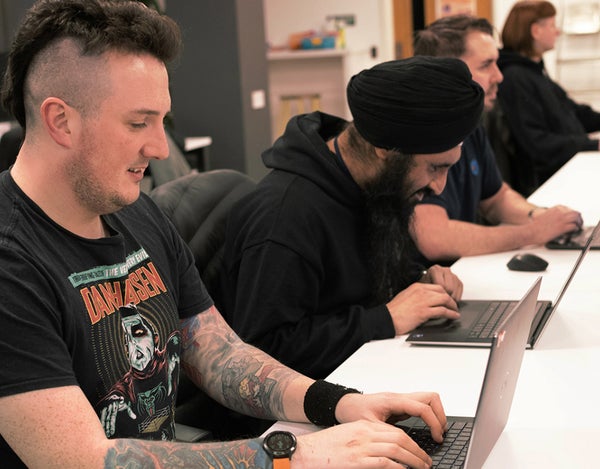 Four 26 employees sat at their desk and looking at their computer screen.