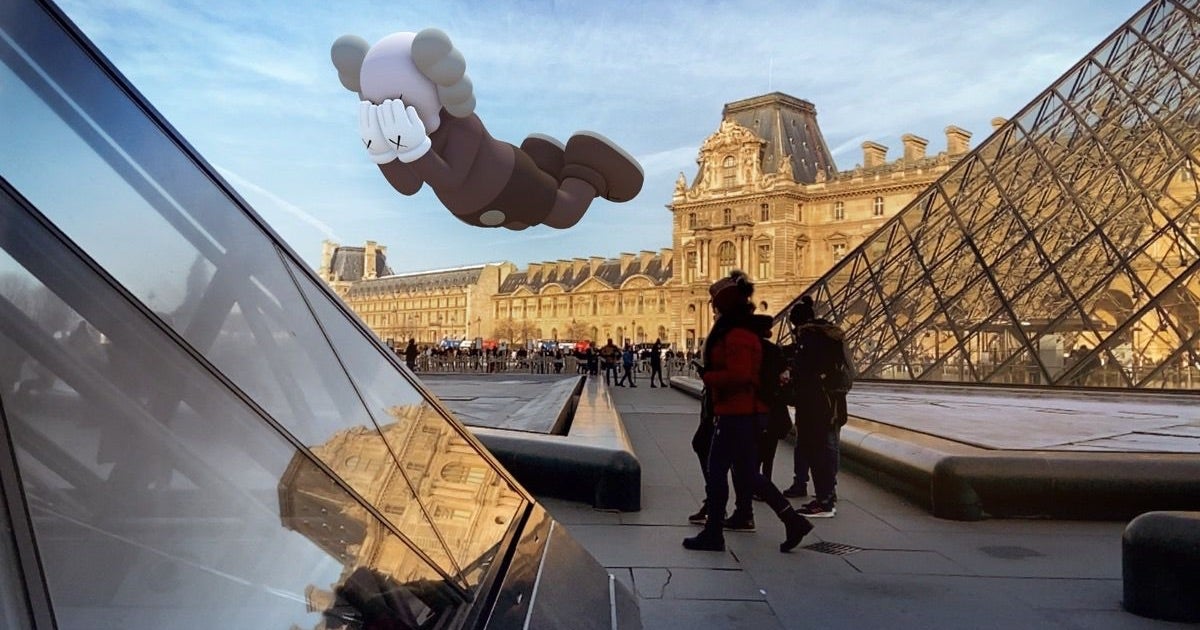 image shows the exterior of the Louvre in Paris with a Kaws statue AR floating above the ground 