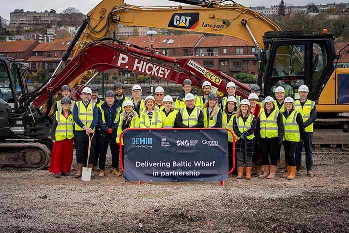 Colleagues from SNG, The Hill Group, Goram Homes, Bristol City Council and Homes England pose in hard helmets on the site of Baltic Wharf.