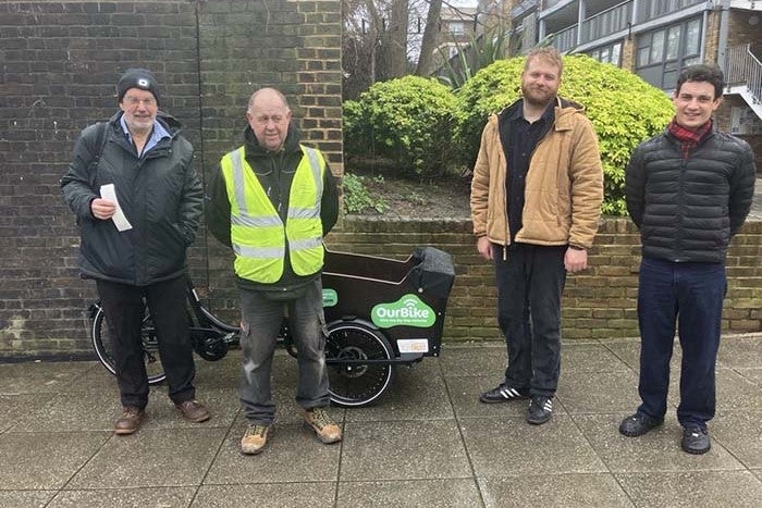 Four men standing beside a tricycle