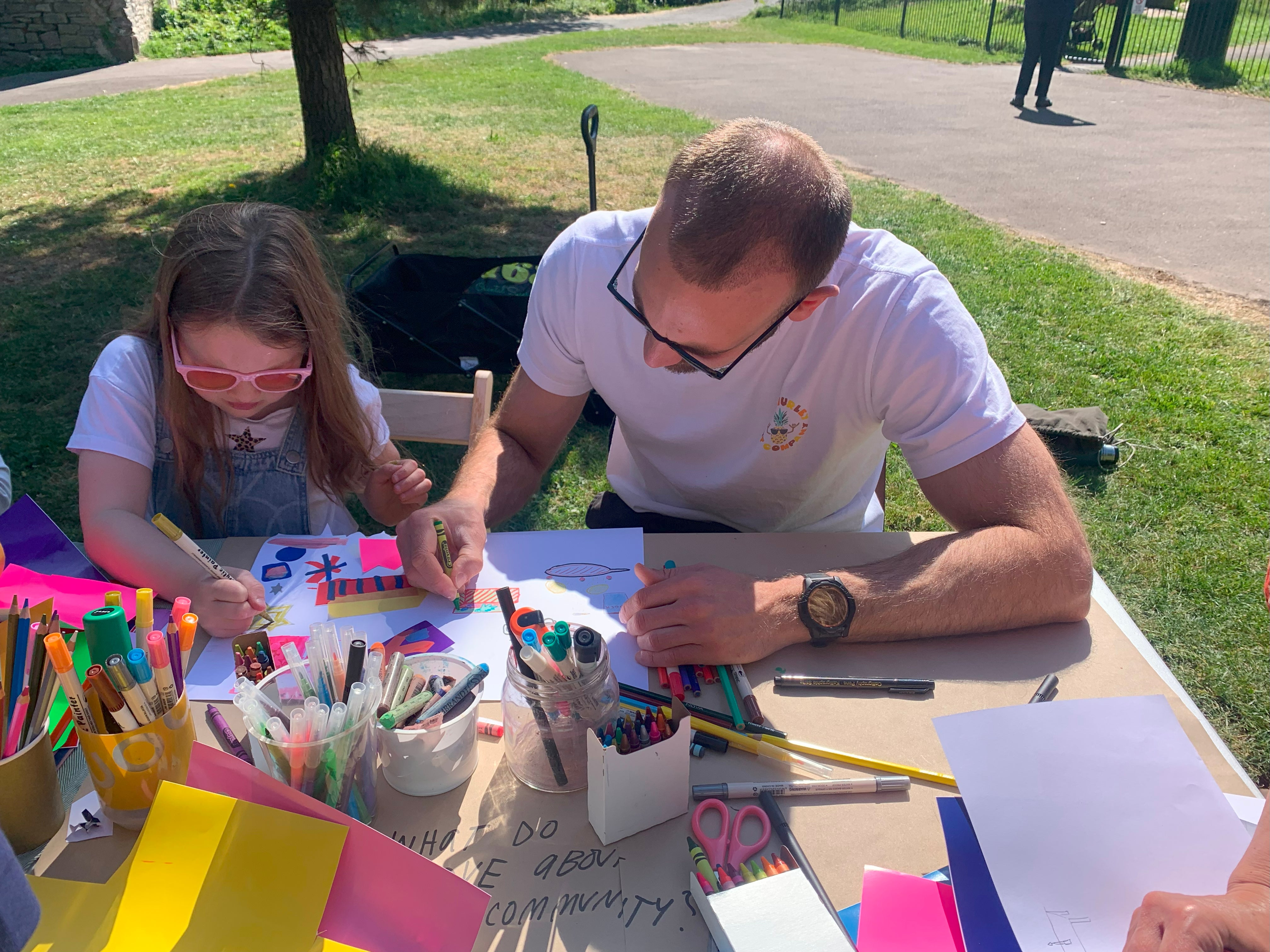 A father and daughter collaborate on a drawing at a community painting event