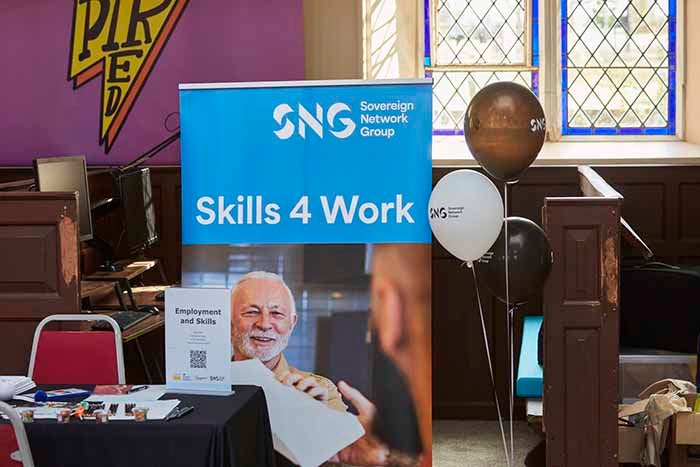 Desk with a pull up banner in the background with 'Skills 4 Work' and a picture of a man.