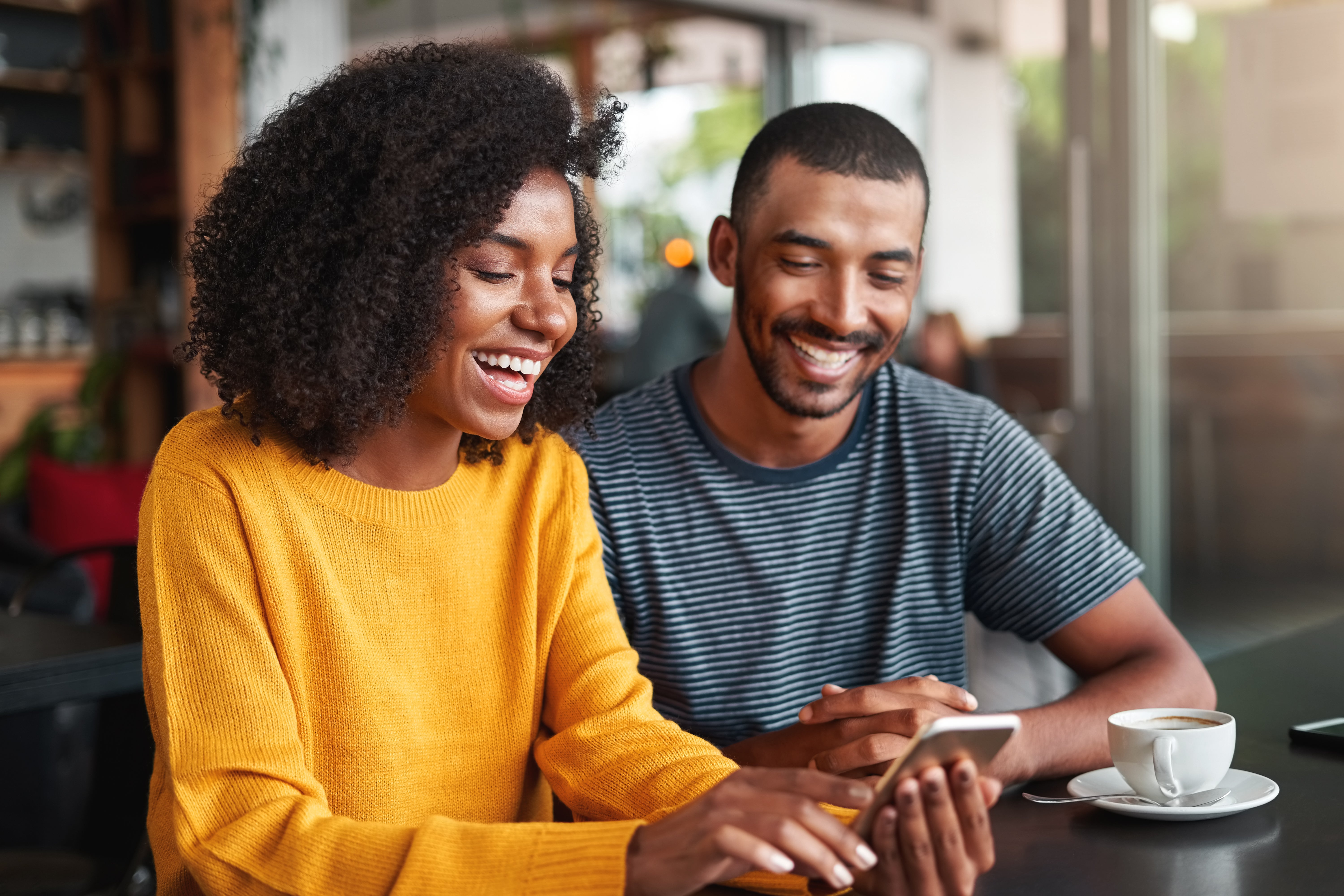 Two people laughing while looking at a mobile device.