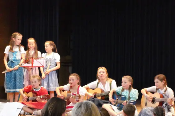 Schülerinnen der GS Lajen singen und musizieren mit Referentin Johanna Mader beim Abschluss des Projektes Musigkischtl im Mai 2024.