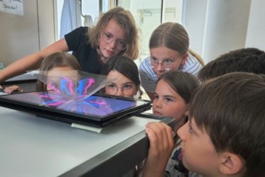 Gespannt blicken die Schülerinnen und Schüler auf das Tablet. (Foto: Deutsche Bildungsdirektion/Alexander Ulbricht)