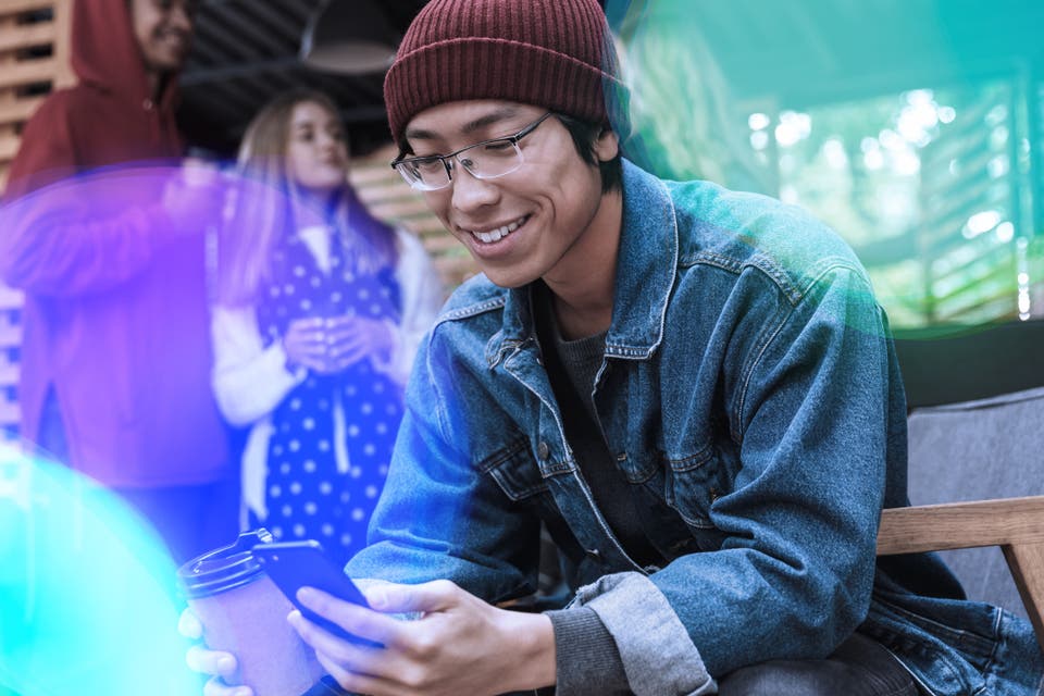 Young professional sitting outside and smiling down while looking at his phone