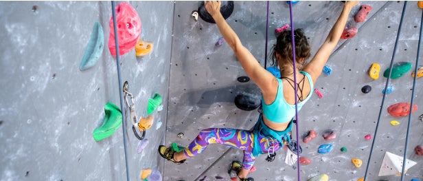 Een jonge vrouw beklimt een klimmuur.