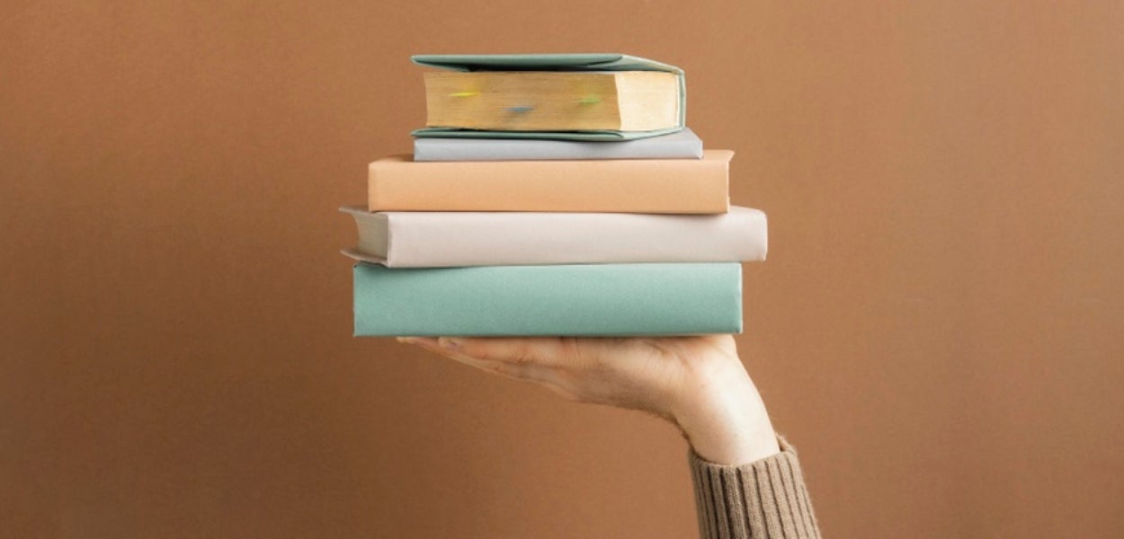 Stapeltje boeken omhooggehouden door hand