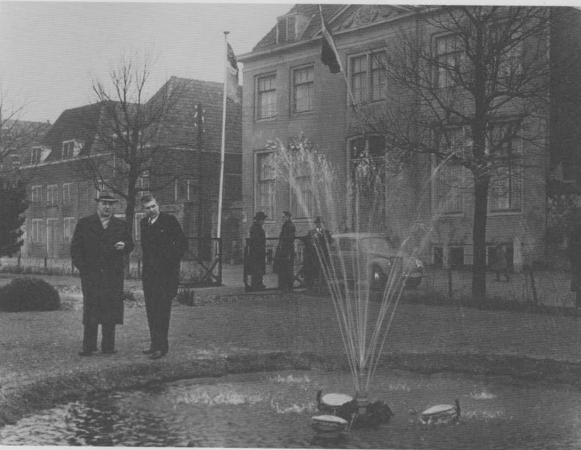 De burgemeester van Hellevoetsluis en de directeur van het waterbedrijf poseren bij een fontein in Hellevoetsluis.