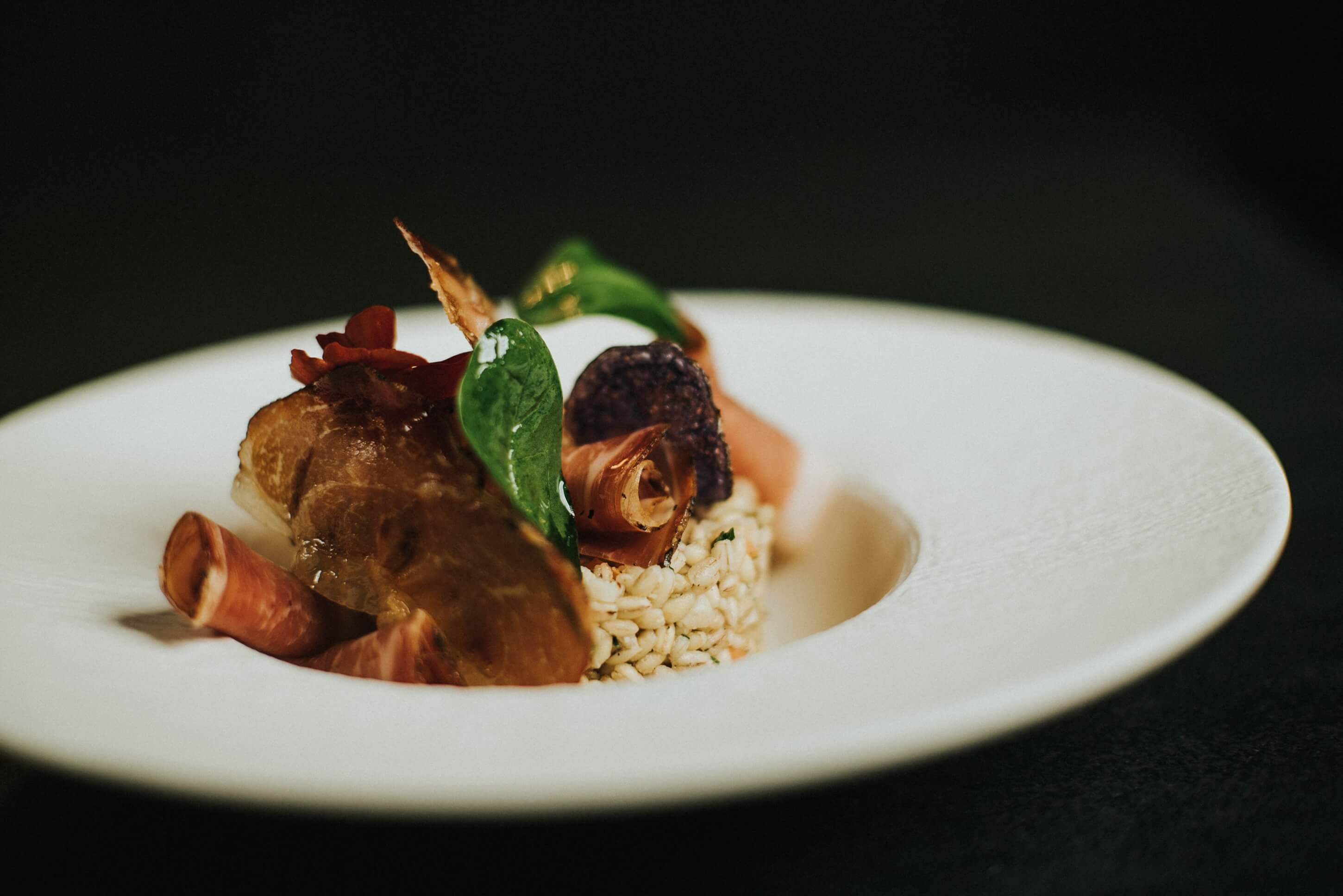 Gerstensalat mit Südtiroler Speck g.g.A. auf Teller angerichtet
