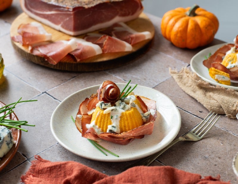Kürbisflan mit Gorgonzola und Südtiroler Speck g.g.A. auf Teller angerichtet