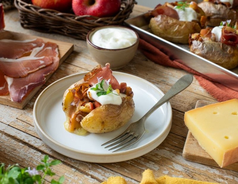 Ofenkartoffel gefüllt mit Pfifferlingen und Südtiroler Speck g.g.A., serviert mit Sauerrahm auf Teller
