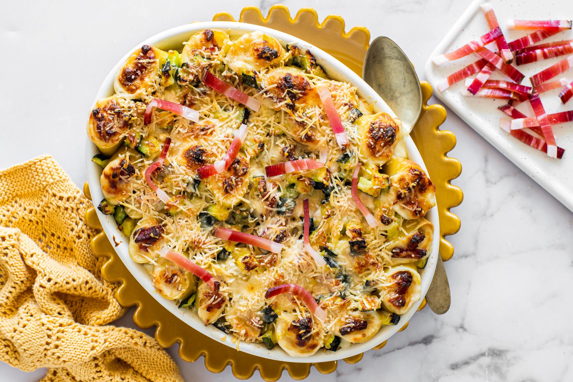 Im Ofen gebackene gefüllte Paccheri mit Südtiroler Speck g.g.A., Zucchini und Lauch, mit Käse überbacken und in einer runden Auflaufform serviert.