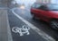 Cycle lane with a red car driving past 