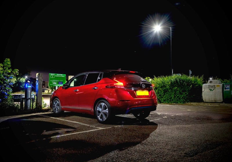Rear view of red Nissan Leaf parking in a public car park at night