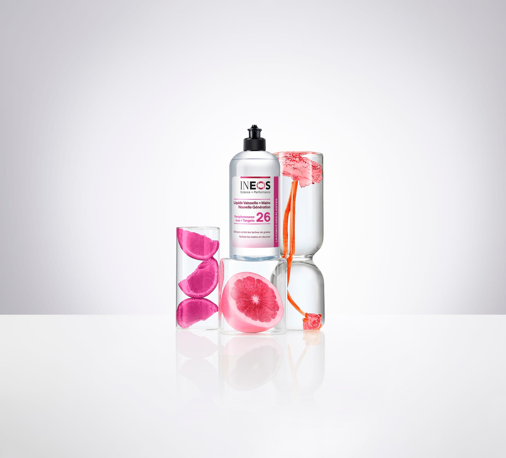 the french version of the pink grapefruit and tangelo 2-in-1 wash next to a sliced pink grapefruit in a white studio