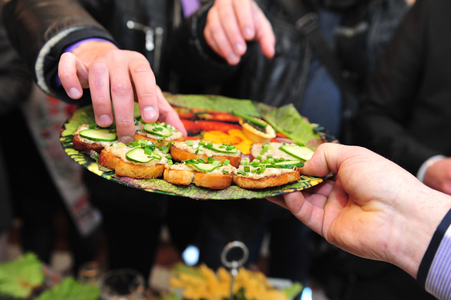 a photo of someone taking some food from a sharing platter