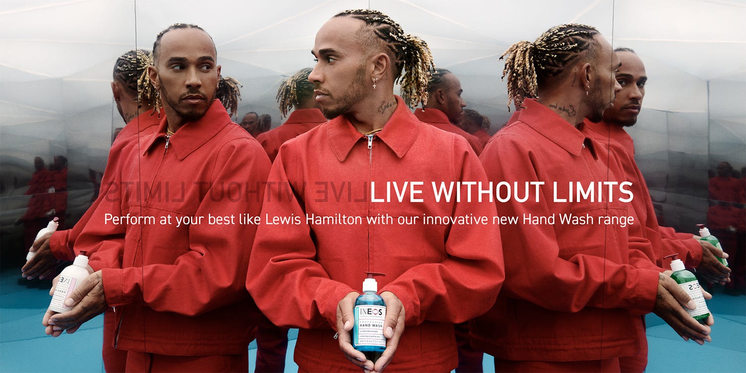 a photo of lewis hamilton in a red shirt holding some sanitiser in room of mirrors