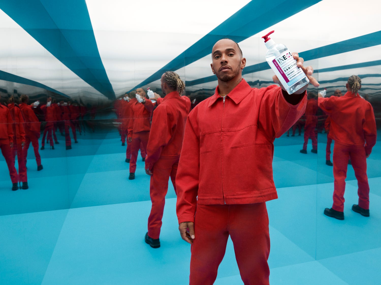 a photo of lewis hamilton in a red shirt holding some sanitiser in room of mirrors