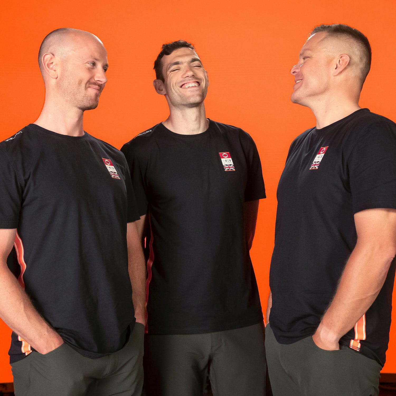 a photo of some members of the britannia sailing team laughing at each other in black shirts