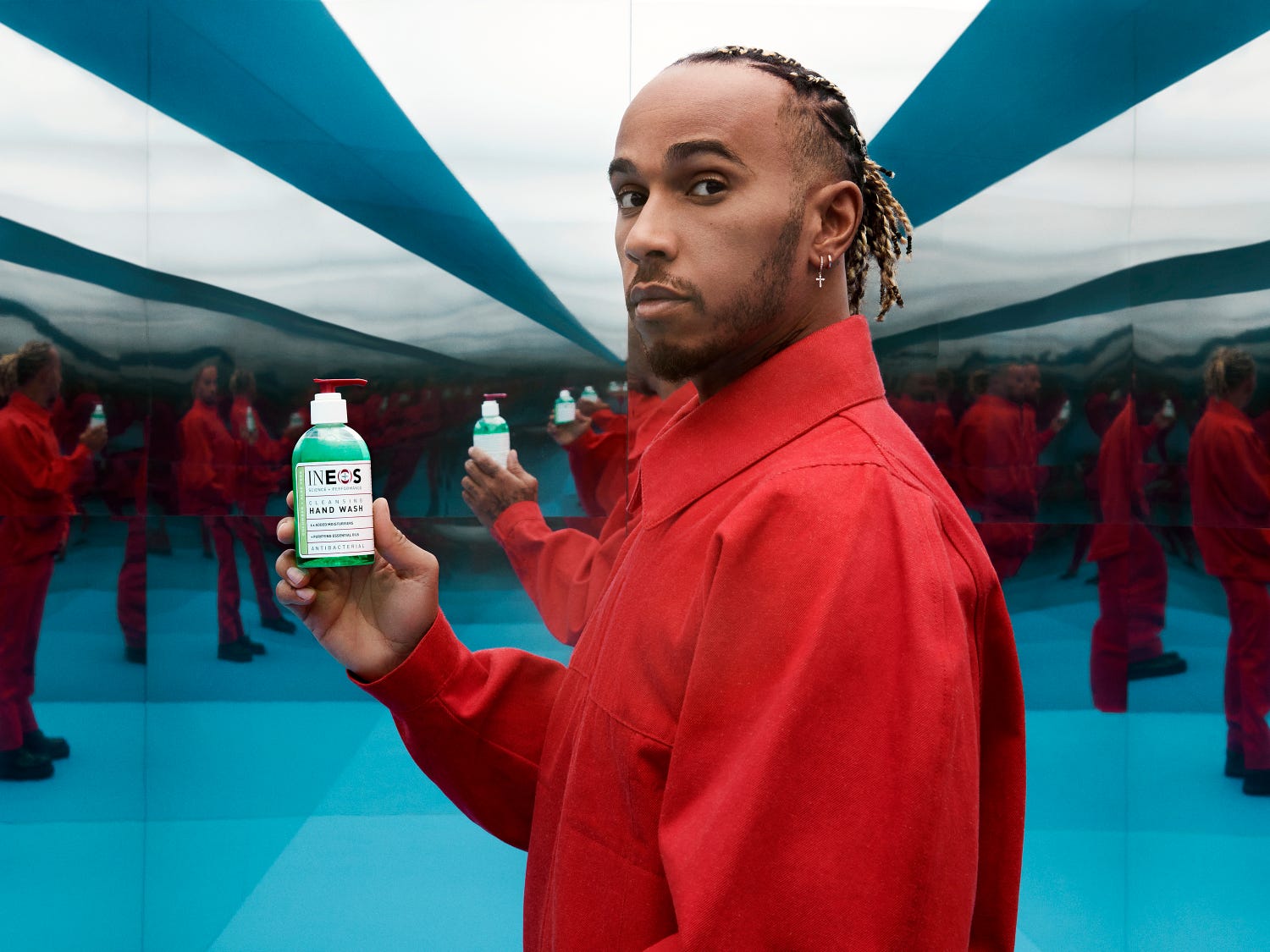 a photo of lewis hamilton in a red shirt holding some sanitiser in room of mirrors