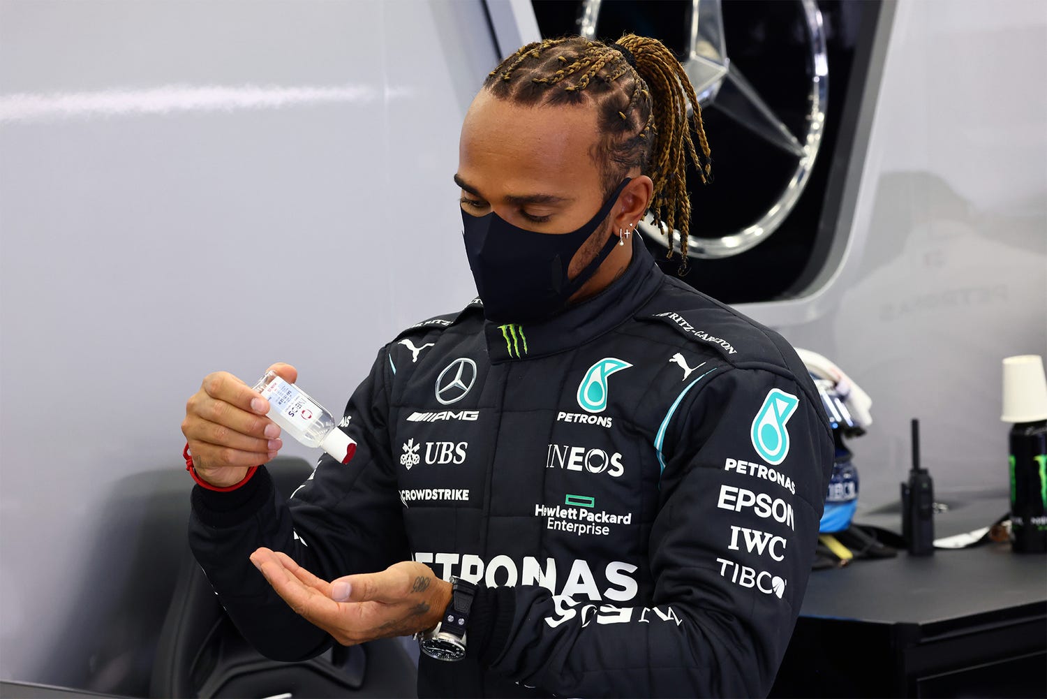 a photo of lewis hamilton in a mask using ineos hygienics hand sanitiser